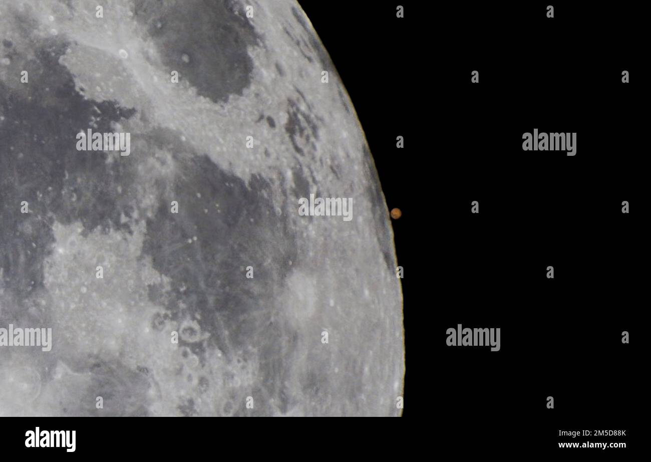 Une vue rapprochée de la réapparition de Mars depuis l'arrière du disque de la pleine Lune, pendant l'occultation de 7 décembre 2022 de Mars. Une partie du dar Banque D'Images