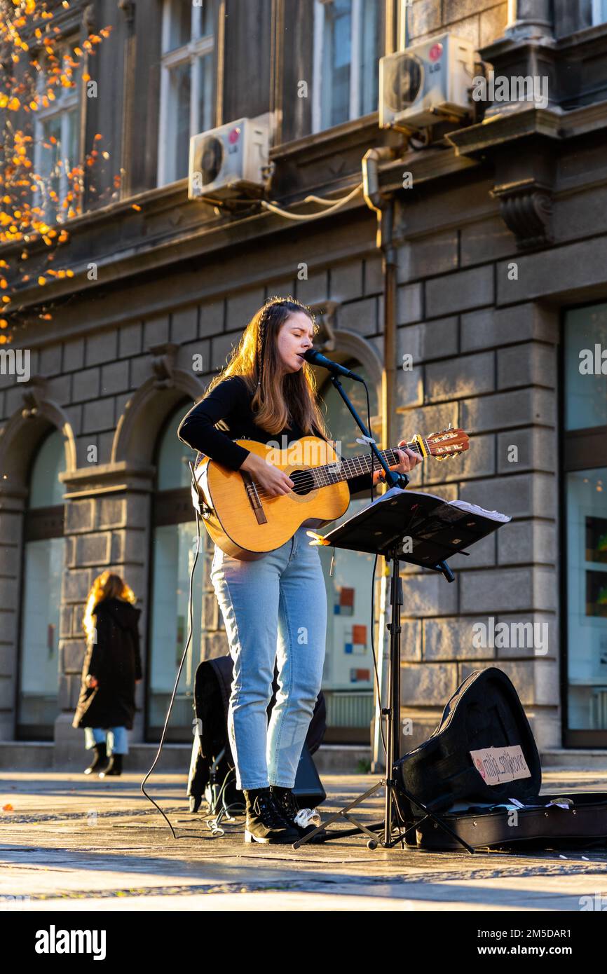 Belgrade, Serbie - 23 décembre 2022 : musicienne jouant de la guitare acoustique et chantant à l'extérieur dans la célèbre rue piétonne Knez Mihailova in Banque D'Images