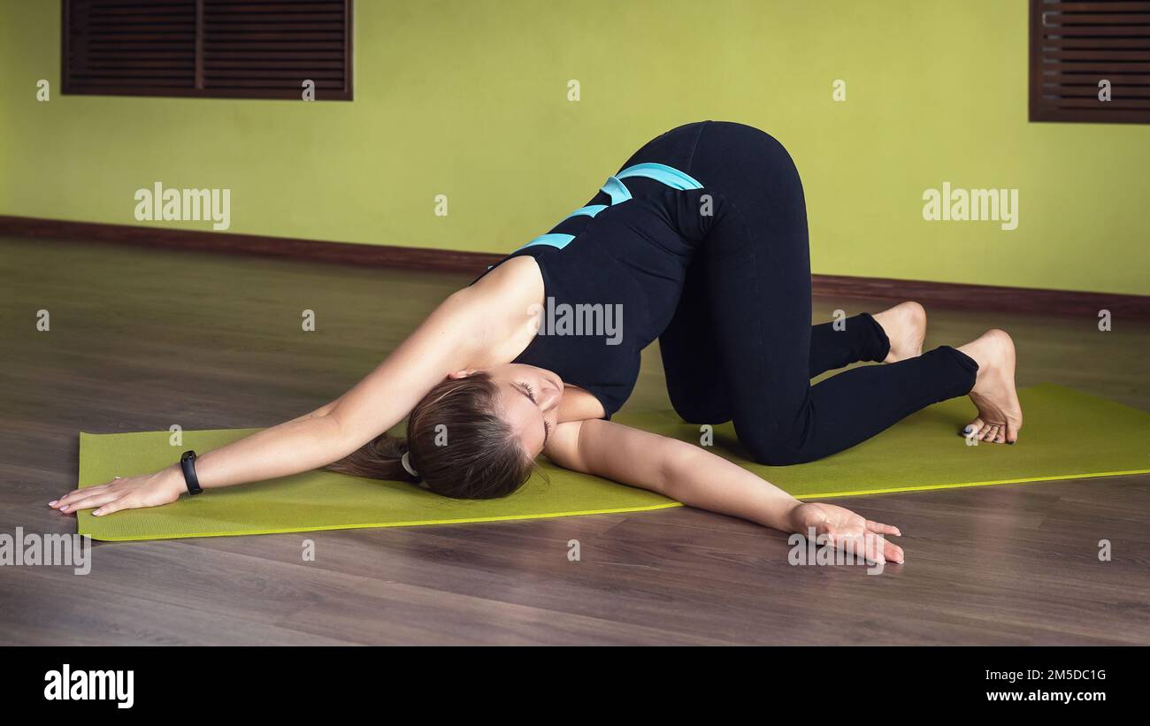 Une femme pratiquant le yoga, faisant une variation de l'exercice Eka Bhuja Swastikasana, une asana pour la flexibilité des articulations de l'épaule, s'entraîne dans Banque D'Images