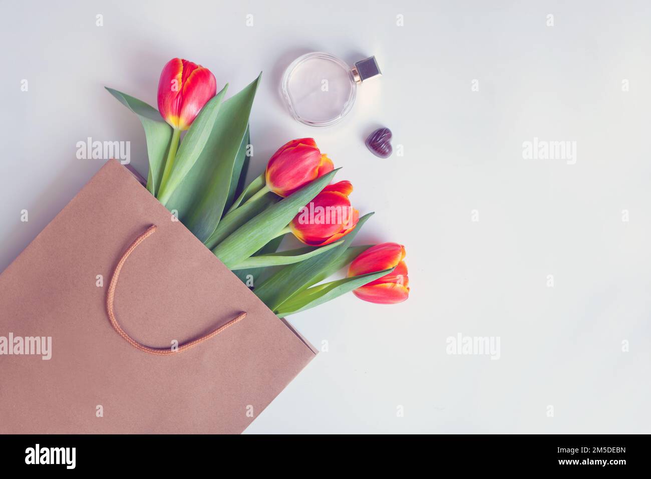 tulipes rouges dans un sac en papier avec parfum. Carte de fleurs avec beau bouquet, cadeau avec espace copie Banque D'Images