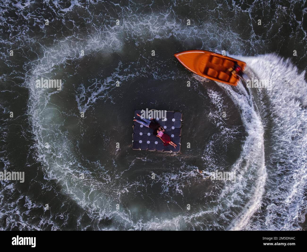 Une vue aérienne en haut d'une surface de mer avec un couple reposant sur un lit flottant et un bateau les entourant Banque D'Images