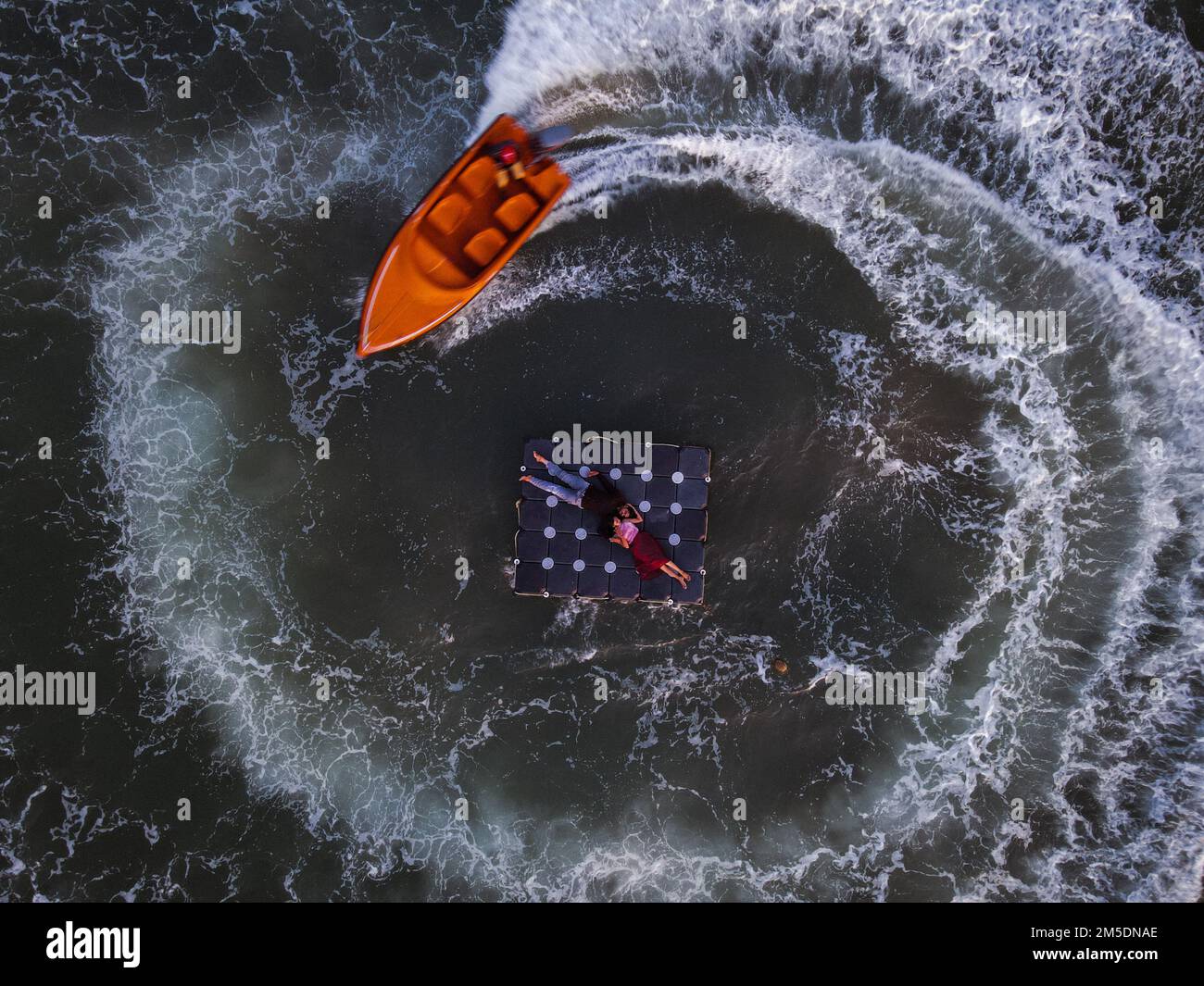 Une vue aérienne en haut d'une surface de mer avec un couple reposant sur un lit flottant et un bateau les entourant Banque D'Images