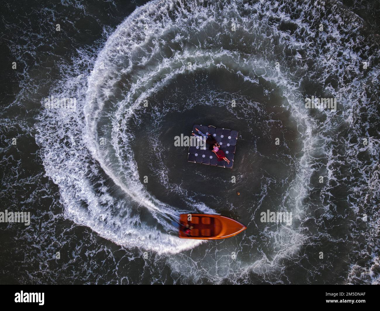 Une vue aérienne en haut d'une surface de mer avec un couple reposant sur un lit flottant et un bateau les entourant Banque D'Images