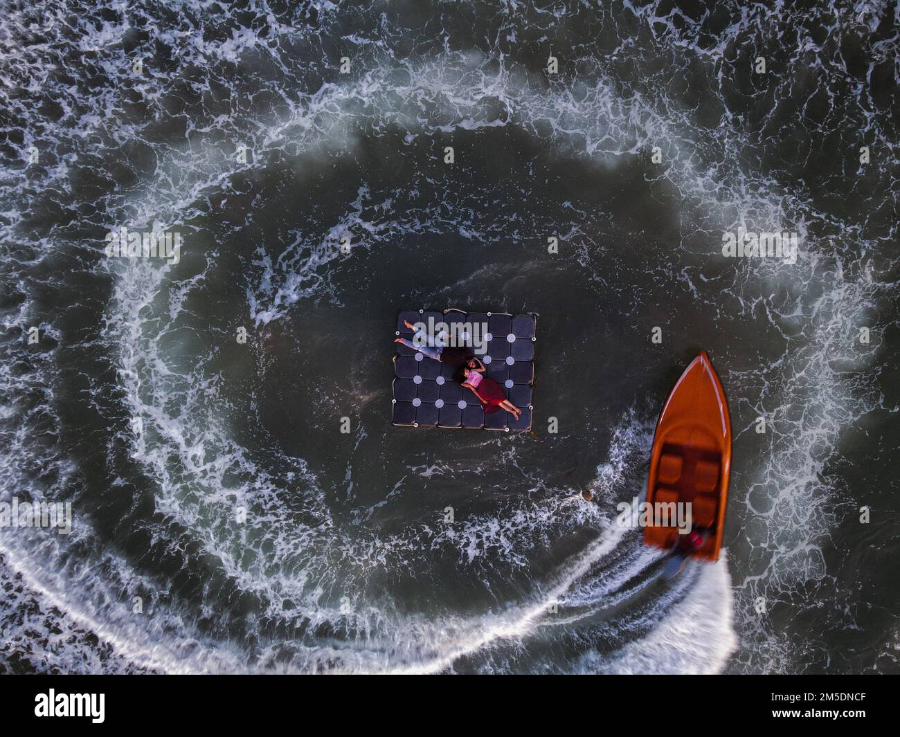 Une vue aérienne en haut d'une surface de mer avec un couple reposant sur un lit flottant et un bateau les entourant Banque D'Images