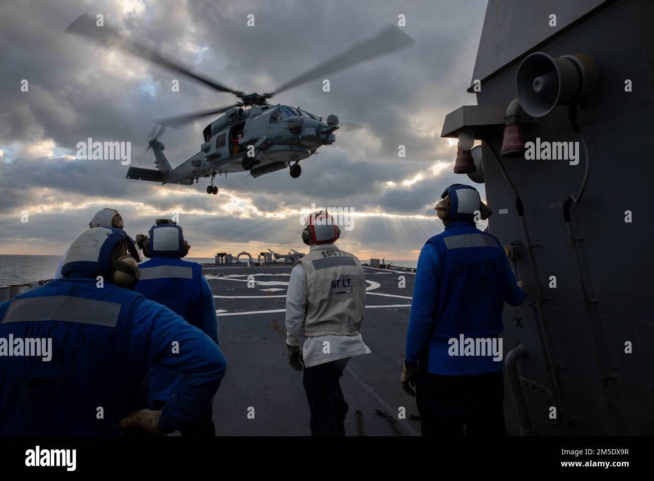 MER DU NORD (5 mars 2022) — les marins affectés au destroyer à missiles guidés USS Donald Cook (DDG 75) regardent un hélicoptère MH-60R Seahawk décolle du pont de vol, 5 mars. Donald Cook est déployé sur le théâtre d'opérations européen et participe à une série d'activités maritimes à l'appui des États-Unis Sixième flotte et alliés de l'OTAN. Banque D'Images