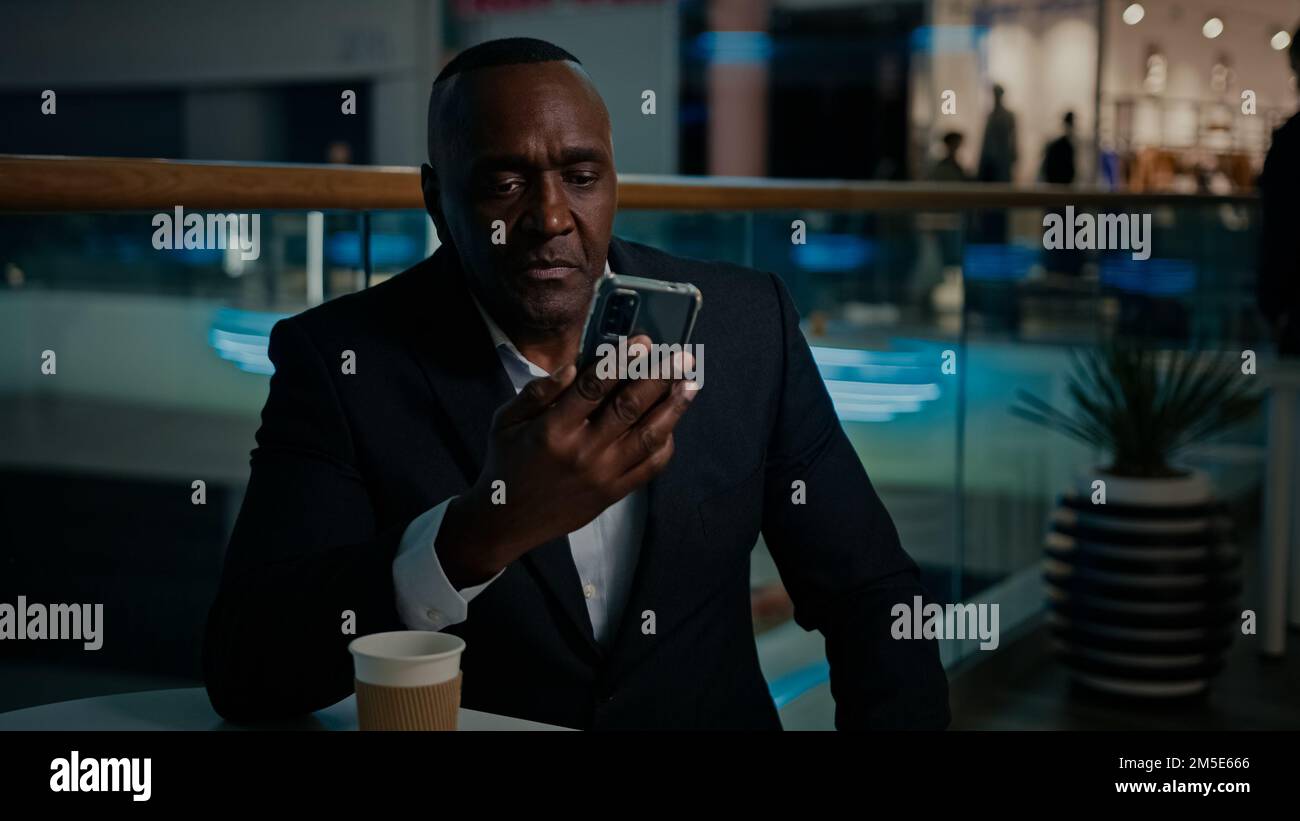 50s Africain ethnique homme d'affaires d'âge moyen parler appel vidéo sérieux avec téléphone mobile conférence répondre sans insatisfait parler avec Banque D'Images