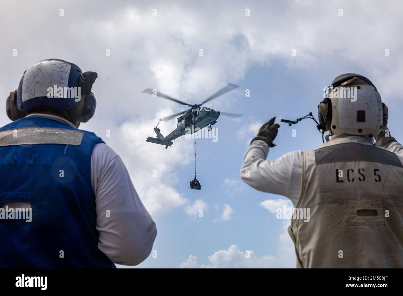 220307-N-HD110-2090 MER DES CARAÏBES - (le 7 mars 2022) -- le compagnon de Boatswain 1st classe Michael Gambrell, à gauche, observe le compagnon de Boatswain 2nd classe James Dowdee signaler aux pilotes dans un hélicoptère MH-60s Sea Hawk attaché aux “Chevaliers de mer” de l’Escadron de combat en mer (HSC) 22, détachement 5, Lors d'une reconstitution verticale (VERTREP) à bord du navire de combat littoral Freedom-variant USS Milwaukee (LCS 5), le 7 mars 2022. Milwaukee est déployée dans la zone d’opérations de la flotte américaine 4th pour soutenir la mission de la Force opérationnelle interagences conjointe Sud, qui comprend la lutte contre le trafic illicite de drogues missi Banque D'Images