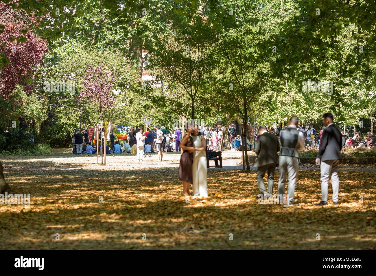 Les gens passent leur temps en premier plan tandis que les participants se rassemblent près du cerisier planté à la mémoire des victimes d'Hiroshima à Londres. Banque D'Images