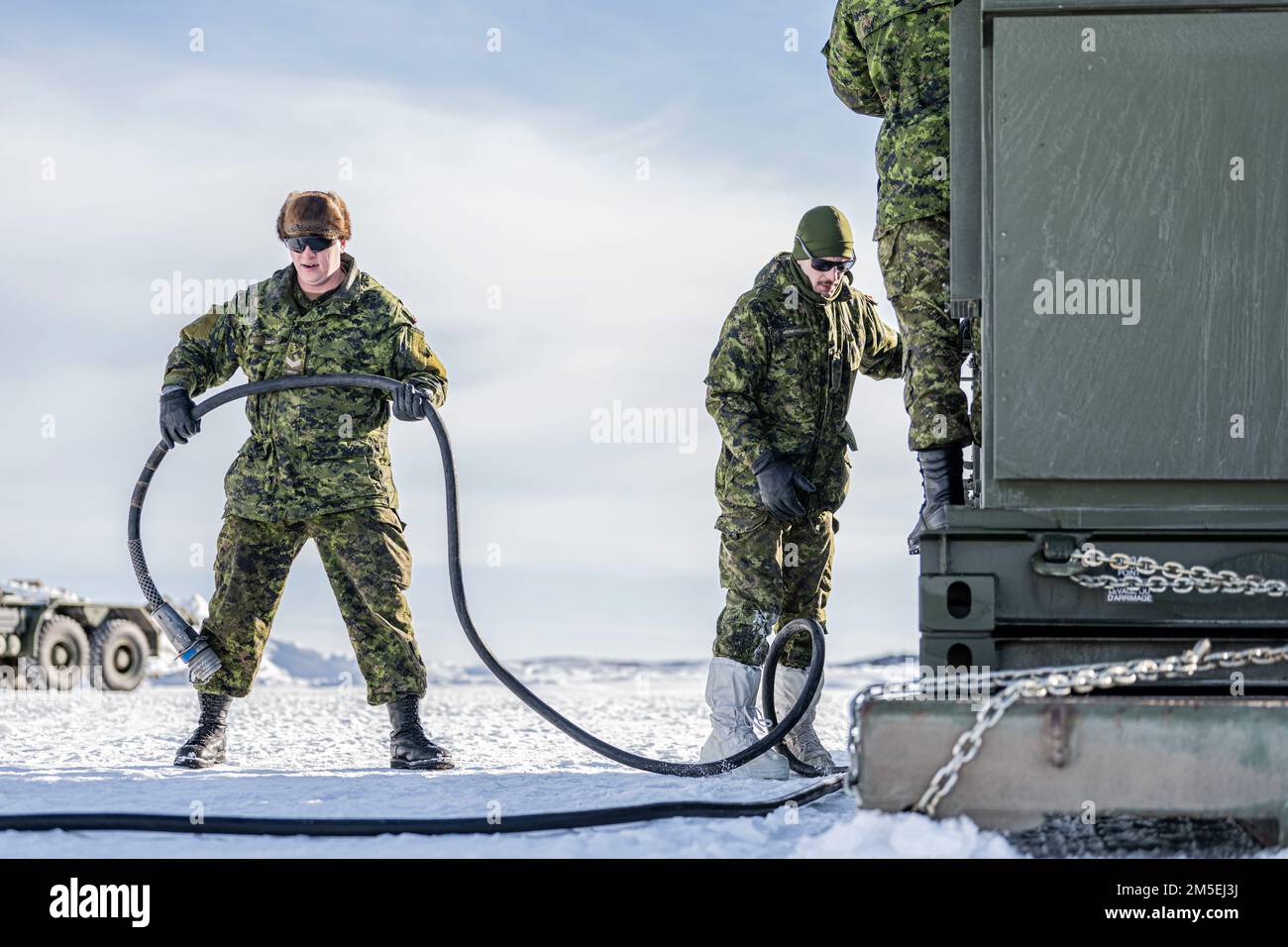 Des soldats de l’Armée canadienne affectés au 4th Régiment d’artillerie, 127th batterie, prolongent un câble d’un générateur pendant l’exercice ARCTIC EDGE 2022 à la base aérienne d’Eielson, Alaska, 8 mars 2022. AE22 est le plus grand exercice conjoint en Alaska, avec environ 1 000 militaires américains formant aux côtés des membres des Forces armées canadiennes pour démontrer leurs capacités dans des conditions météorologiques froides austères. Banque D'Images