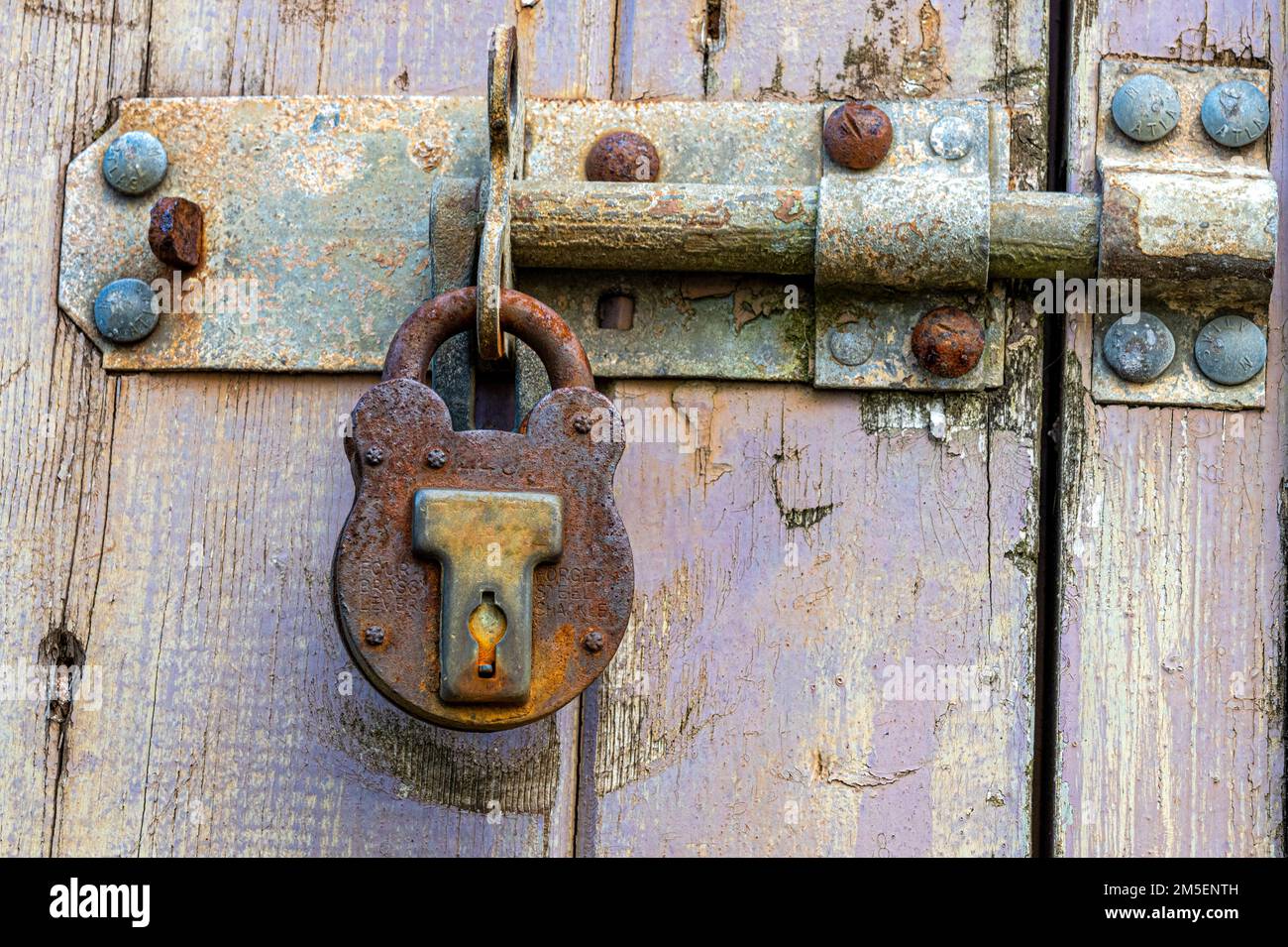 Boulon rouillé et cadenas dans une ancienne porte en bois Banque D'Images