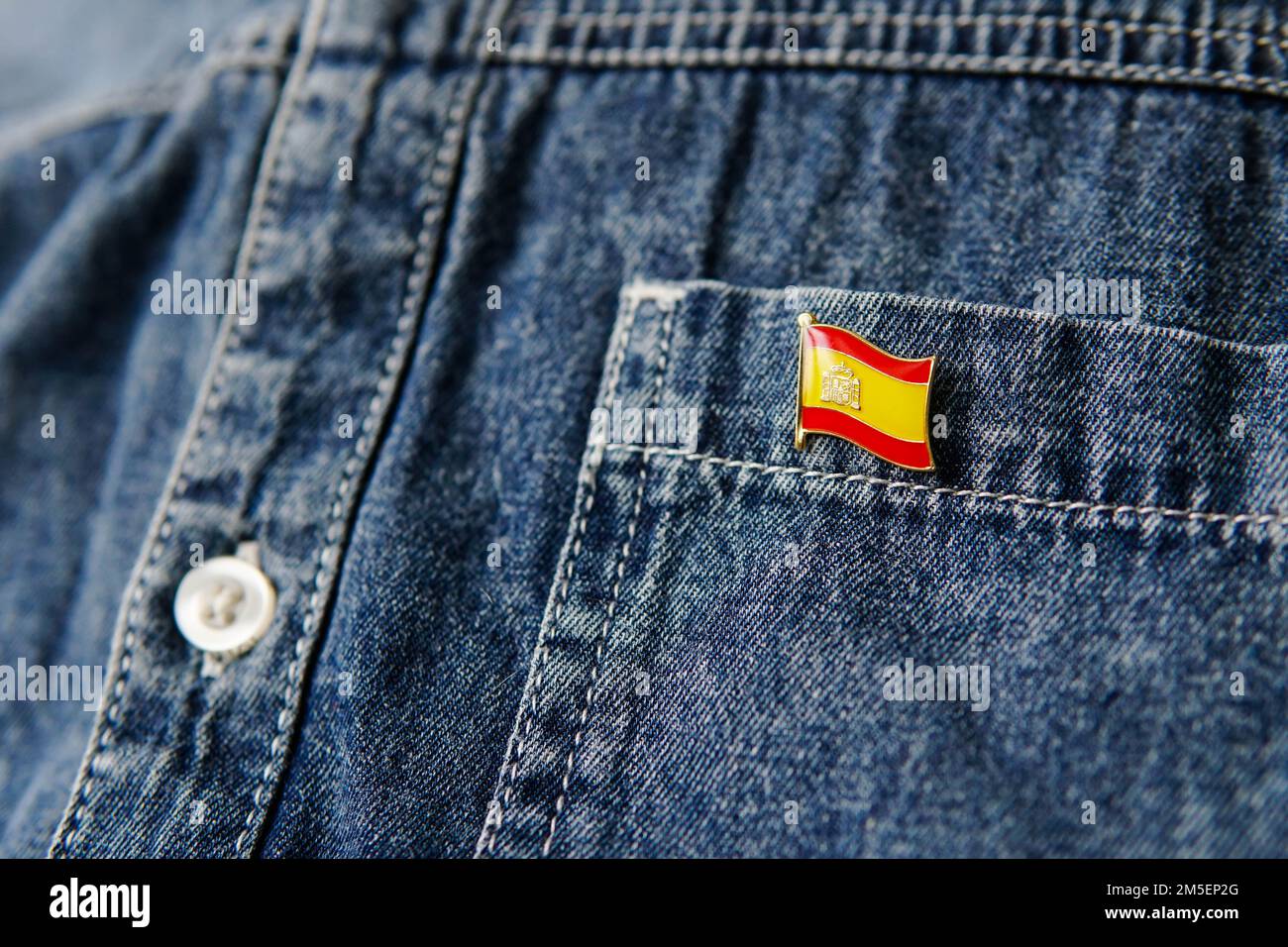 Badge en métal avec le drapeau de l'Espagne est épinglé sur la veste bleue de Jean. Espagne patriotisme concept. Jour de l'indépendance en Espagne. Banque D'Images