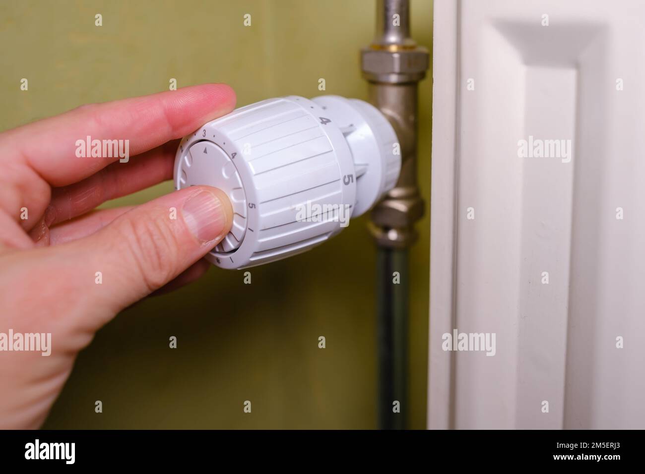 Augmentation des coûts de chauffage en crise, l'homme règle la température à la maison avec le thermostat de chauffage pour économiser l'énergie, gros plan Banque D'Images