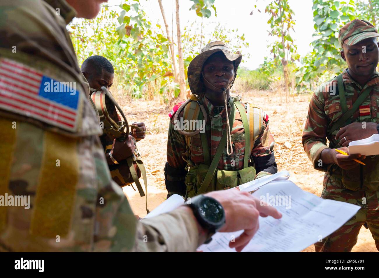 A ÉTATS-UNIS Le Béret vert de l'armée affecté au 3rd Groupe des forces spéciales (Airborne) discute des détails d'un ordre d'opérations (OPORD) avec des soldats béninois lors d'un exercice d'entraînement sur le terrain au Bénin, en Afrique, au 09 mars 2022. L’engagement international est nécessaire pour lutter contre l’extrémisme violent, et nos engagements militaires ne sont qu’un moyen pour nous de soutenir les partenaires africains dans le cadre d’une communauté internationale. Banque D'Images