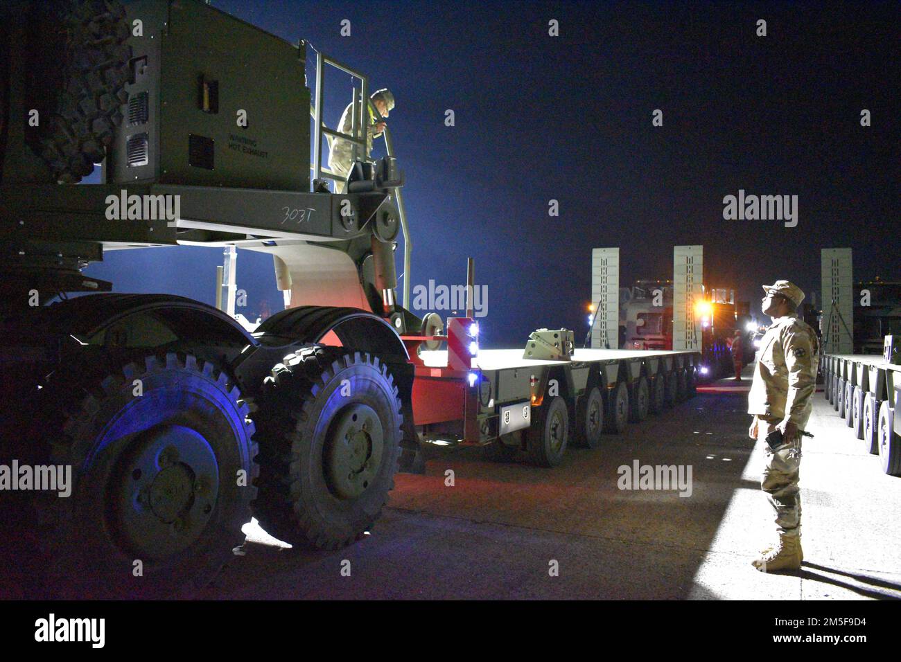 Le général Aguilar du SPC, à gauche, 51st Compagnie de camions composites, 18th Bataillon de soutien au combat, 16th Brigade de soutien, discute avec le Sgt. 1st classe Willard Corbin, à droite, 96th Compagnie de transport d'équipement lourd, 49th Bataillon des transports, 13th Commandement du maintien expéditionnaire, Alors qu'ils préparent les derniers tracteurs de camions Bobtail et les remorques d'équipement lourd améliorées pour être prêts à voyager 10 mars 2022 au dépôt militaire de Zutendaal, en Belgique. Banque D'Images