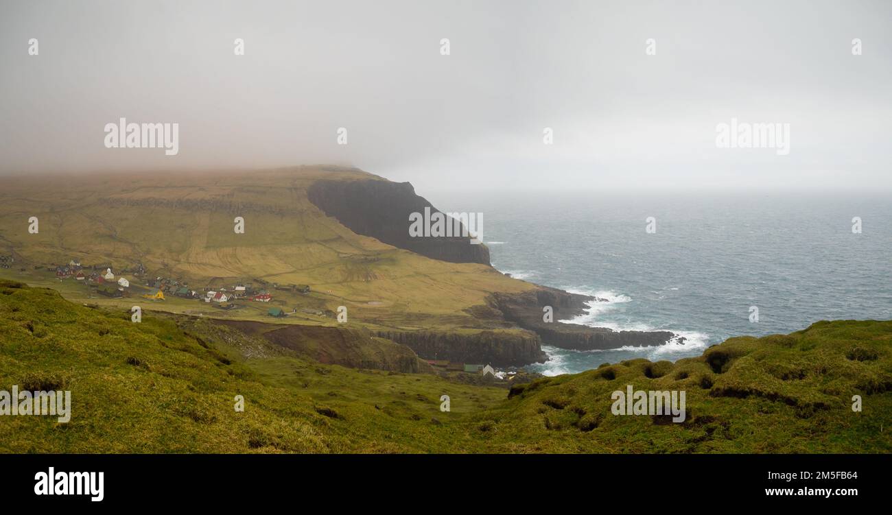 Village de Mykines au bord de la mer entre les champs d'herbe vus de Mykineshólmur Banque D'Images