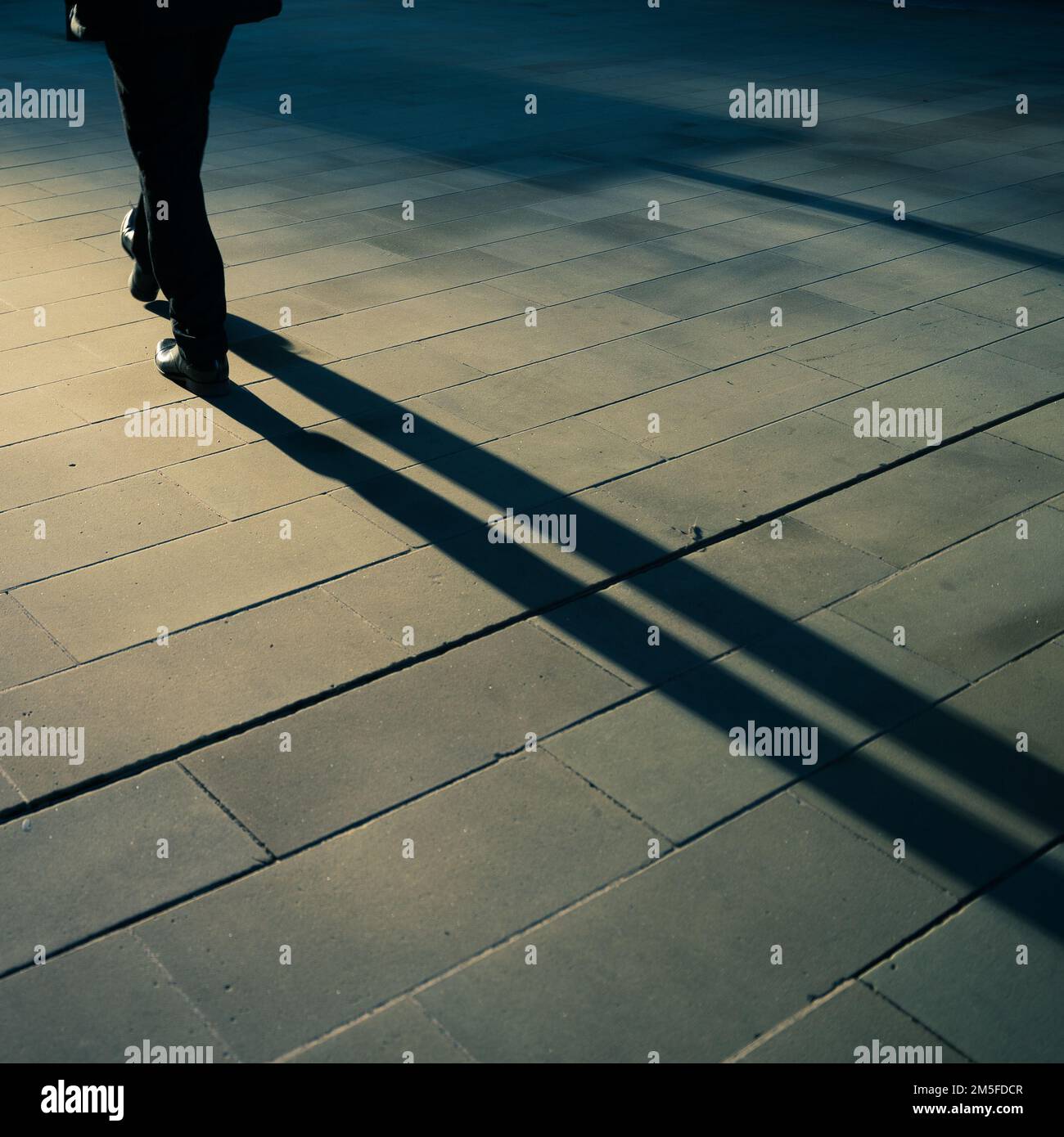 Longues ombres d'un homme marchant à Londres, tôt le matin. Teinte bleue. Banque D'Images
