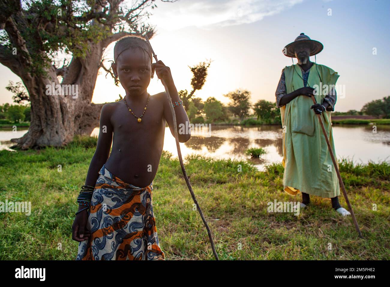 Shepherd Fulani , Peul homme avec un chapeau traditionnel et une jeune fille à côté du lac au Mali, Afrique de l'Ouest. Banque D'Images