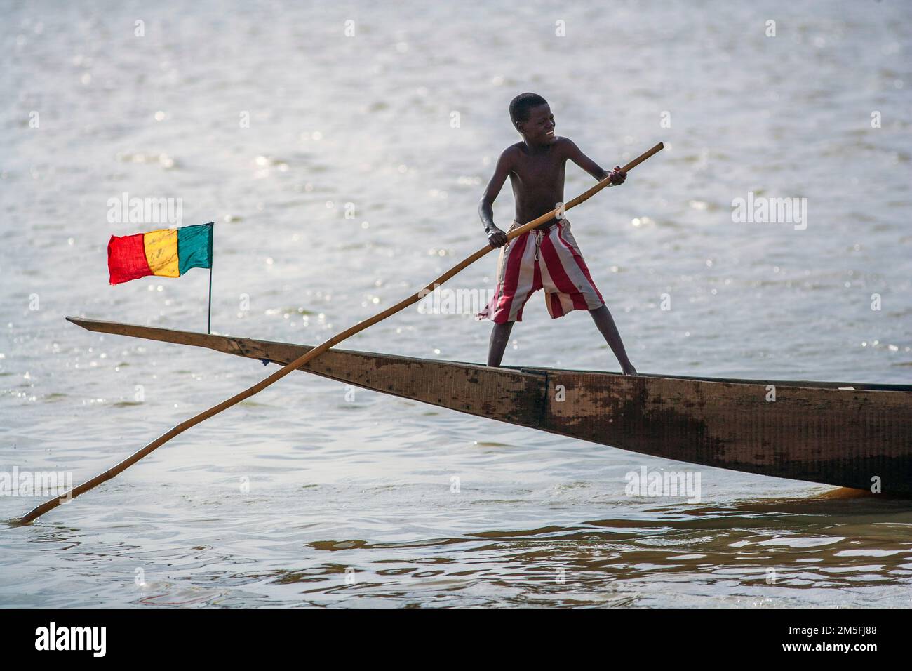 Un pirogue avec le drapeau national du mali et l'enfant à Mopti, Mali, Afrique de l'Ouest. Banque D'Images