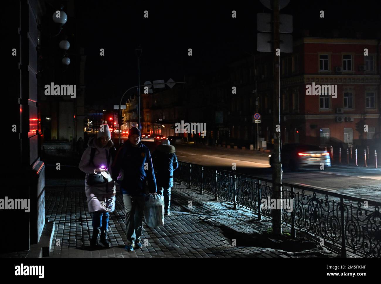 Kiev, Ukraine. 26th décembre 2022. Les gens descendent une rue sombre pendant une panne de courant à Kiev. L'armée russe a mené des attaques massives de roquettes et de drones kamikaze sur les infrastructures énergétiques ukrainiennes. Après de graves dommages au réseau électrique dans de nombreuses villes d'Ukraine, la compagnie nationale d'électricité Ukrenergo a introduit des coupures d'électricité d'urgence et toutes les heures. Crédit : SOPA Images Limited/Alamy Live News Banque D'Images