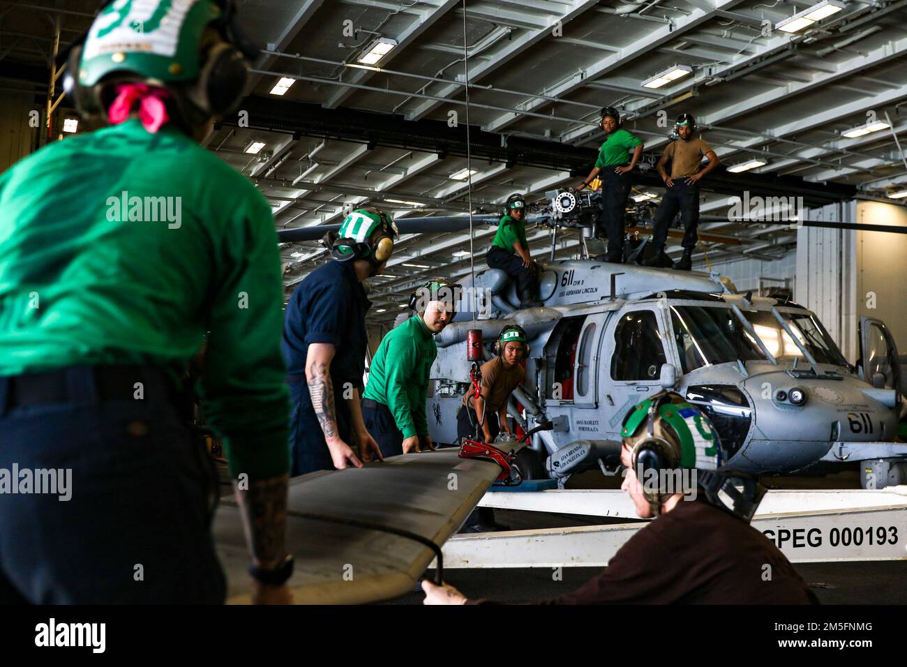 Les marins DE LA MER DES PHILIPPINES (15 mars 2022) lèvent une lame de rotor qui sera attachée à un hélicoptère MH-60s Sea Hawk, affecté aux “Chargers” de l’Escadron de combat de la mer (HSC) 14, dans la baie hangar à bord du porte-avions de la classe Nimitz USS Abraham Lincoln (CVN 72). Abraham Lincoln Strike Group est en cours de déploiement prévu dans la zone d'exploitation de la flotte américaine 7th afin d'améliorer l'interopérabilité par le biais d'alliances et de partenariats tout en servant de force de réaction prête à l'emploi pour soutenir une région libre et ouverte d'Indo-Pacifique. Banque D'Images