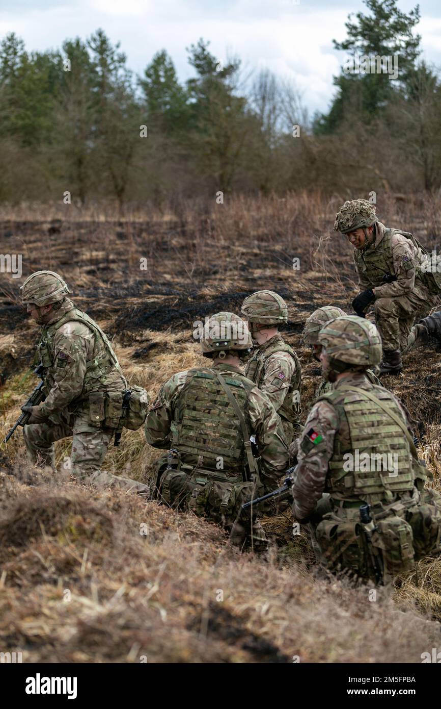 Les cadets de l'officier de l'armée britannique avec l'Académie militaire royale de Sandhurst se sont prêts à passer par une ligne d'entraînement de feu en direct en tant qu'équipe, dans la zone d'entraînement de Grafenwoehr du Commandement de l'instruction de l'armée américaine 7th, Grafenwoehr, Allemagne, 14 mars 2022. L'exercice d'entraînement a été le point culminant des leçons récentes de tactiques de combat rapproché démontées qui les ont forcées à travailler à l'unisson et à réfléchir rapidement pour atteindre un objectif dans un domaine inconnu. Banque D'Images