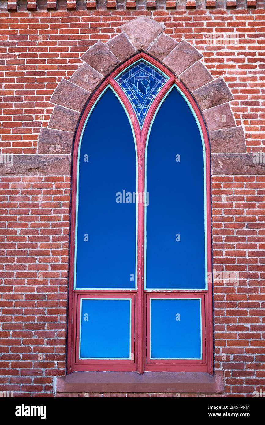 Ancienne fenêtre voûtée avec verre teinté dans un bâtiment en brique Banque D'Images
