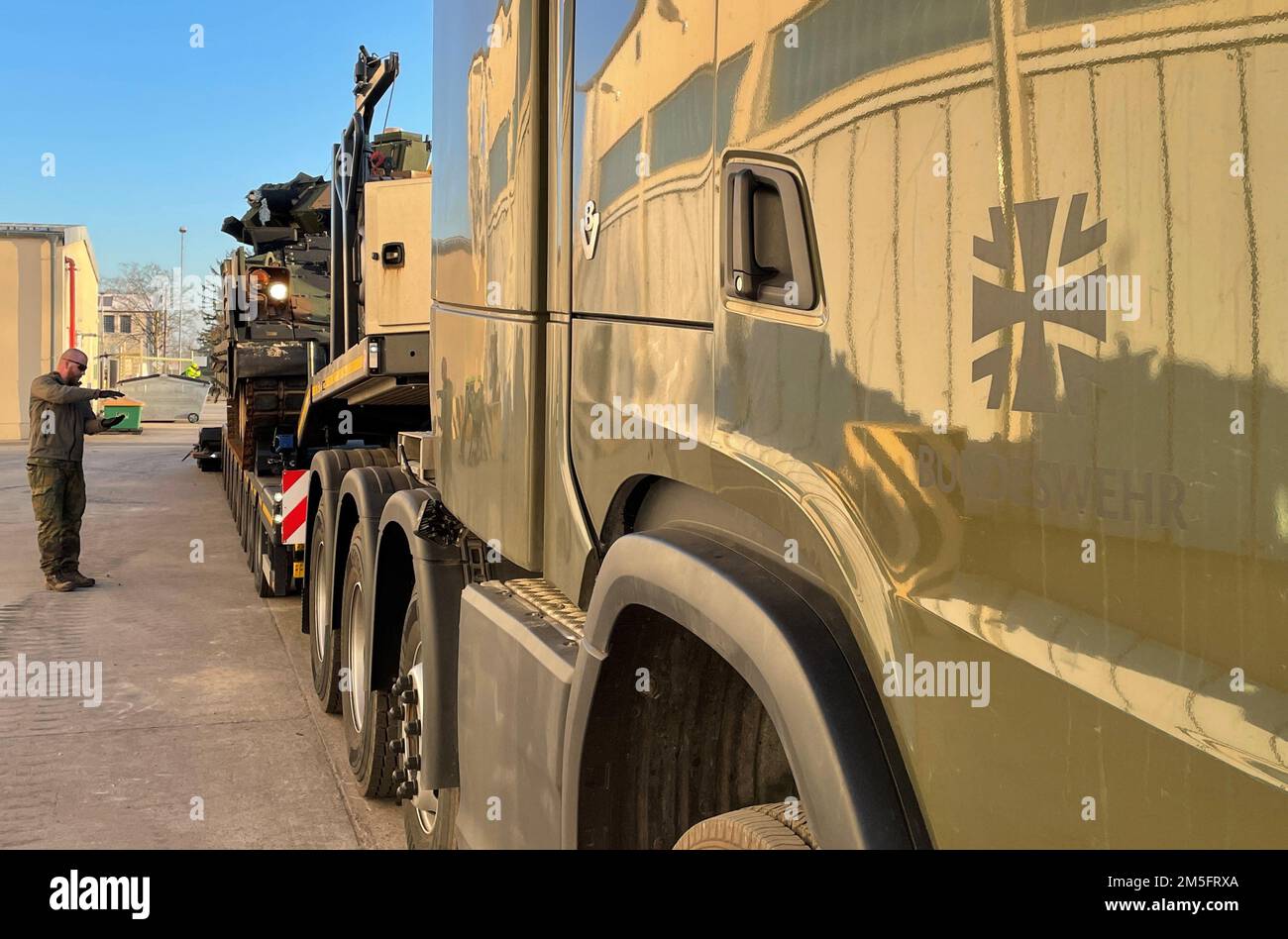 Un soldat allemand au sol guide un chauffeur alors qu'il charge un américain L'armée Bradley combat un véhicule sur un transporteur d'équipement lourd de l'armée allemande sur le site de Coleman à Mannheim, en Allemagne. Ces ETH allemands nouvellement acquis aident à livrer 405th Brigade de soutien sur le terrain de l'Armée de terre de préposition stocks-2 véhicules et équipement du chantier de Coleman à Grafenwoehr, en Allemagne, où l'APS-2 est délivré aux forces américaines déployées. L’AFSB de 405th a pleinement activé ses sites APS-2, et pour la première fois dans l’histoire du programme APS-2 de la brigade, elle a pour mission de surpasser tout le personnel de l’équipe de combat d’une brigade blindée Banque D'Images