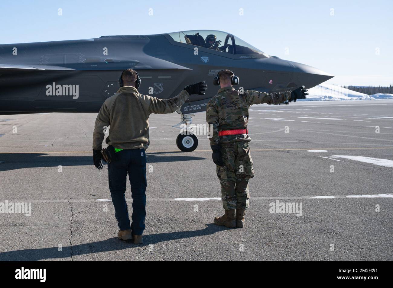 Depuis la gauche, États-Unis Airman Aleksandr Zenski, un compagnon de gestion de véhicule de l'escadron de préparation logistique 354th; le Maj Jonathan Bucey, un pilote F-35 de l'escadron de combat 356th; Et Airman 1st classe Ian Sears, un chef d’équipage de l’unité d’entretien des aéronefs de 356th, rend hommage à l’escadron lors d’une immersion « Chef d’équipage pour une journée » sur la base aérienne d’Eielson, en Alaska, au 15 mars 2022. Au cours de l’immersion, les chefs d’équipage «honoraires» accompagnent le personnel d’entretien au cours des inspections, du lancement, de la récupération et du ravitaillement des aéronefs affectés. Banque D'Images