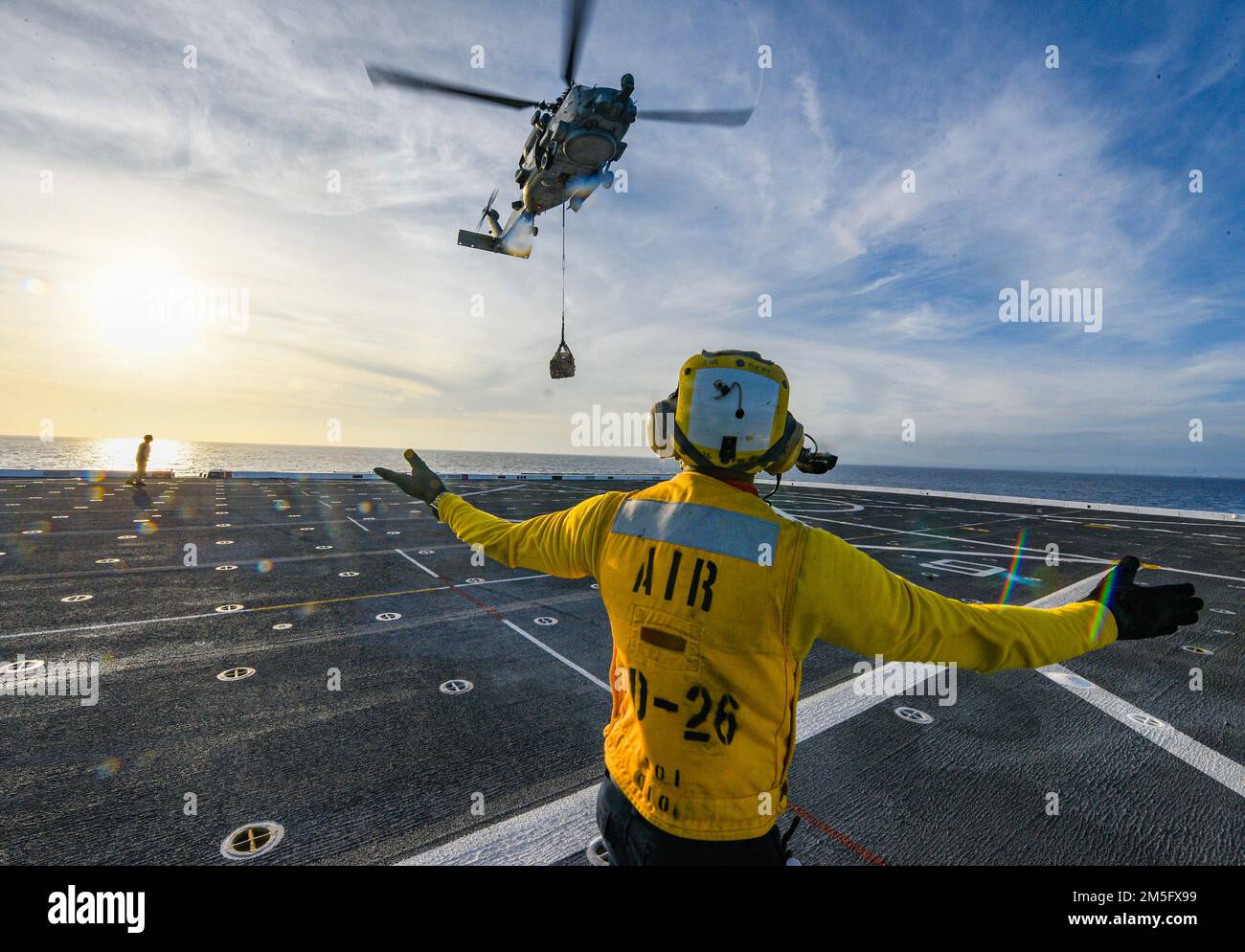 OCÉAN PACIFIQUE (15 mars 2022) Aviation Boatswain’s Mate 3rd classe Kyro Lee, de Miami, affecté au navire de quai de transport amphibie USS John P. Murtha (LPD 26), dirige un hélicoptère MH-60s Seahawk attaché aux “Easy Riders” de l’Escadron de frappe maritime d’hélicoptère (HSM) 37 pour monter lors d’un réapprovisionnement vertical en mer (TRVEREP), 15 mars. John P. Murtha mène actuellement des opérations de routine dans la flotte américaine 3rd. Banque D'Images