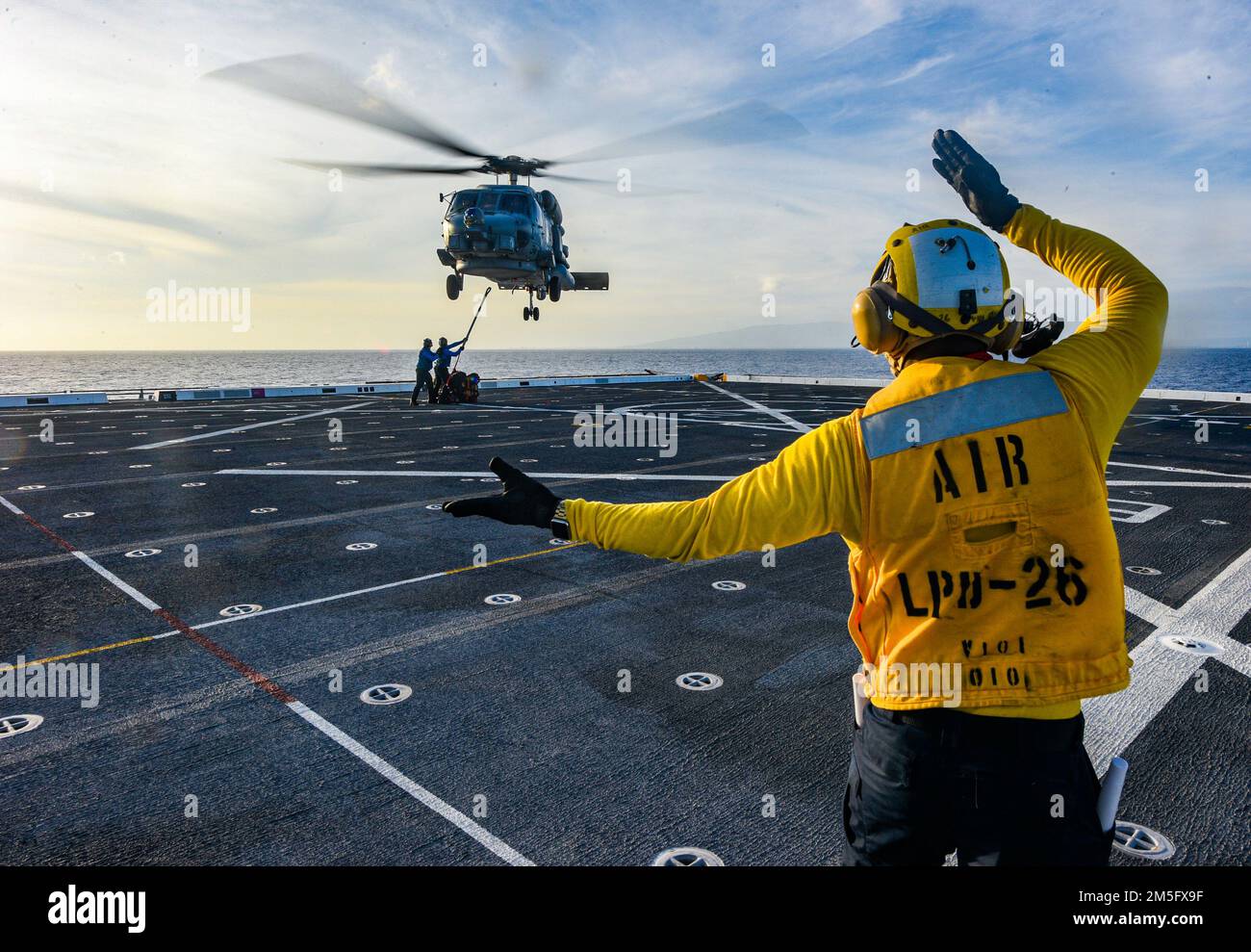 OCÉAN PACIFIQUE (15 mars 2022) Aviation Boatswain’s Mate 3rd classe Kyro Lee, de Miami, affecté au navire de quai de transport amphibie USS John P. Murtha (LPD 26), Ordonne à un hélicoptère MH-60s Seahawk attaché aux « Easy Riders » de l’Escadron de frappe maritime (UGV) 37 de se mettre en place pendant un réapprovisionnement vertical en mer (VERTREP), à 15 mars. John P. Murtha mène actuellement des opérations de routine dans la flotte américaine 3rd. Banque D'Images