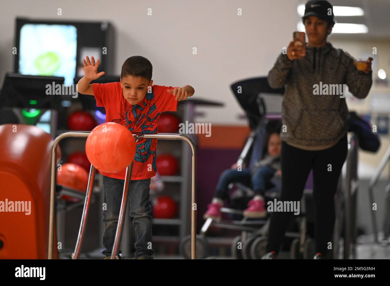 AJ Janinda laisse passer un appel de bowling lors d'un événement Hearts Apart à la base aérienne de Hanscom, Massachusetts, 16 mars, tandis que sa mère, Kurstie Janinda, regarde. Le programme Hearts Apart d'Airman and Family Readiness Center offre aux familles de personnel temporaire déployé ou prolongé des activités sociales qui leur permettent de se réunir, de construire des amitiés et de soulager la tension de la séparation de leurs proches. Pour obtenir de plus amples renseignements, communiquez avec Le Crf De L'A&FRC au 781-225-2765. (É.-U. Photo de la Force aérienne Todd Maki) Banque D'Images