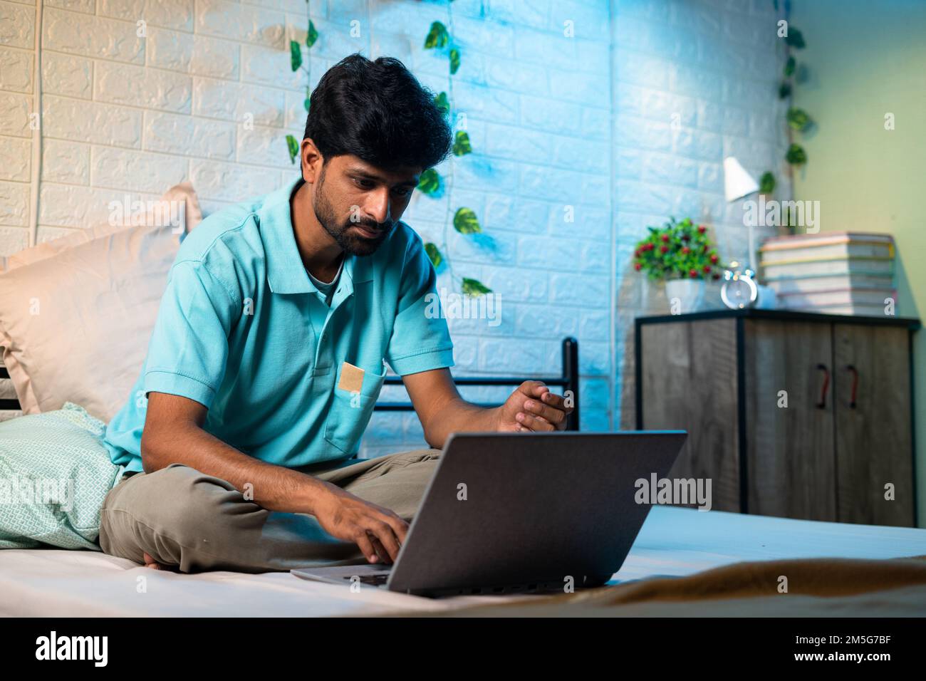 jeune homme occupé woking sur ordinateur portable et nuit sur lit - concept de travail excessif, travail à la maison et échéance du projet Banque D'Images
