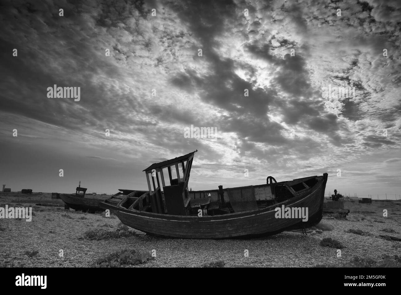 Brisés jetées de bateaux de pêche sur une plage de galets avec un paysage spectaculaire et nuageux, cimetière de bateaux, noir et blanc, Dungeness, Kent, Angleterre Banque D'Images