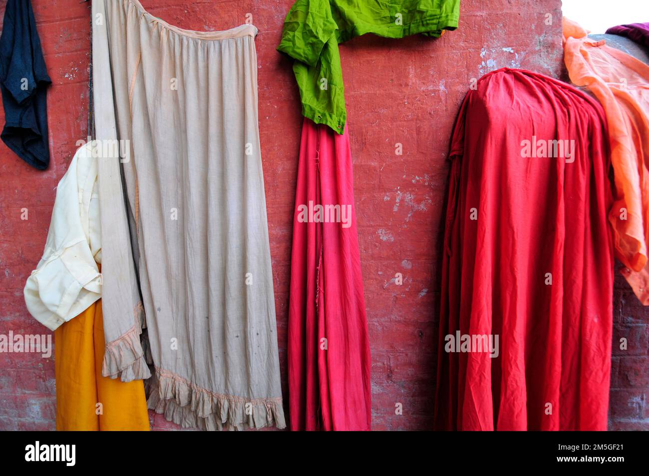 Tissu suspendu par un mur rouge à Babughat, Kolkata, Inde. Banque D'Images