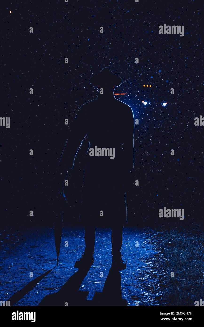 silhouette d'un détective masculin dans un chapeau et un imperméable avec un parapluie sur une rue de nuit de pluie Banque D'Images