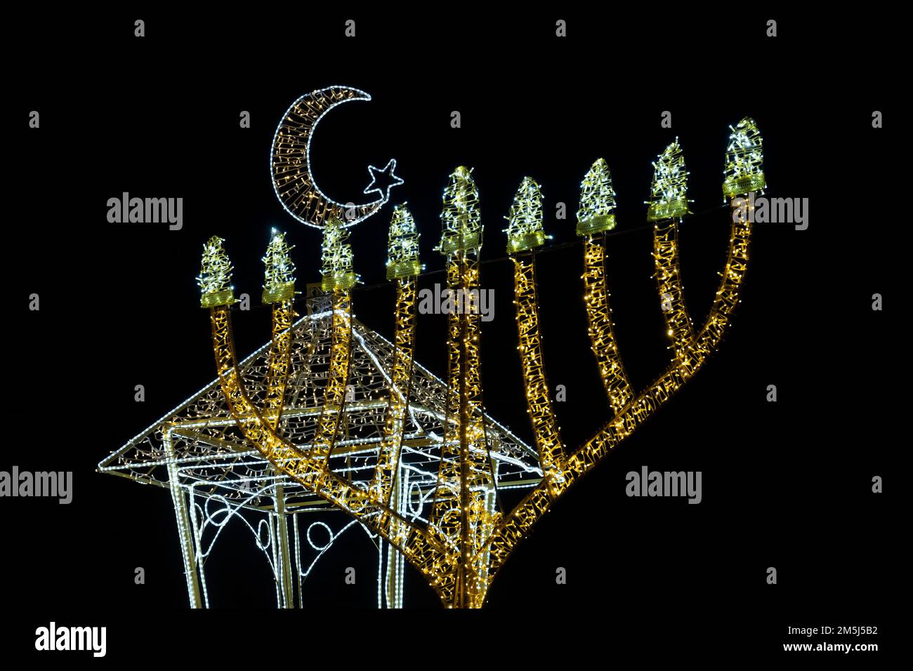 Illuminé la menorah d'Hanoukkah et le croissant de la nouvelle lune qui est associée à l'Islam, affiché dans le quartier de la colonie allemande à Haïfa, Israël comme la ville célèbre les fêtes de vacances qui marque les fêtes d'Hanoukkah, Noël, et Ramadan de trois religions principales: Le christianisme, le judaïsme et l'Islam. Banque D'Images