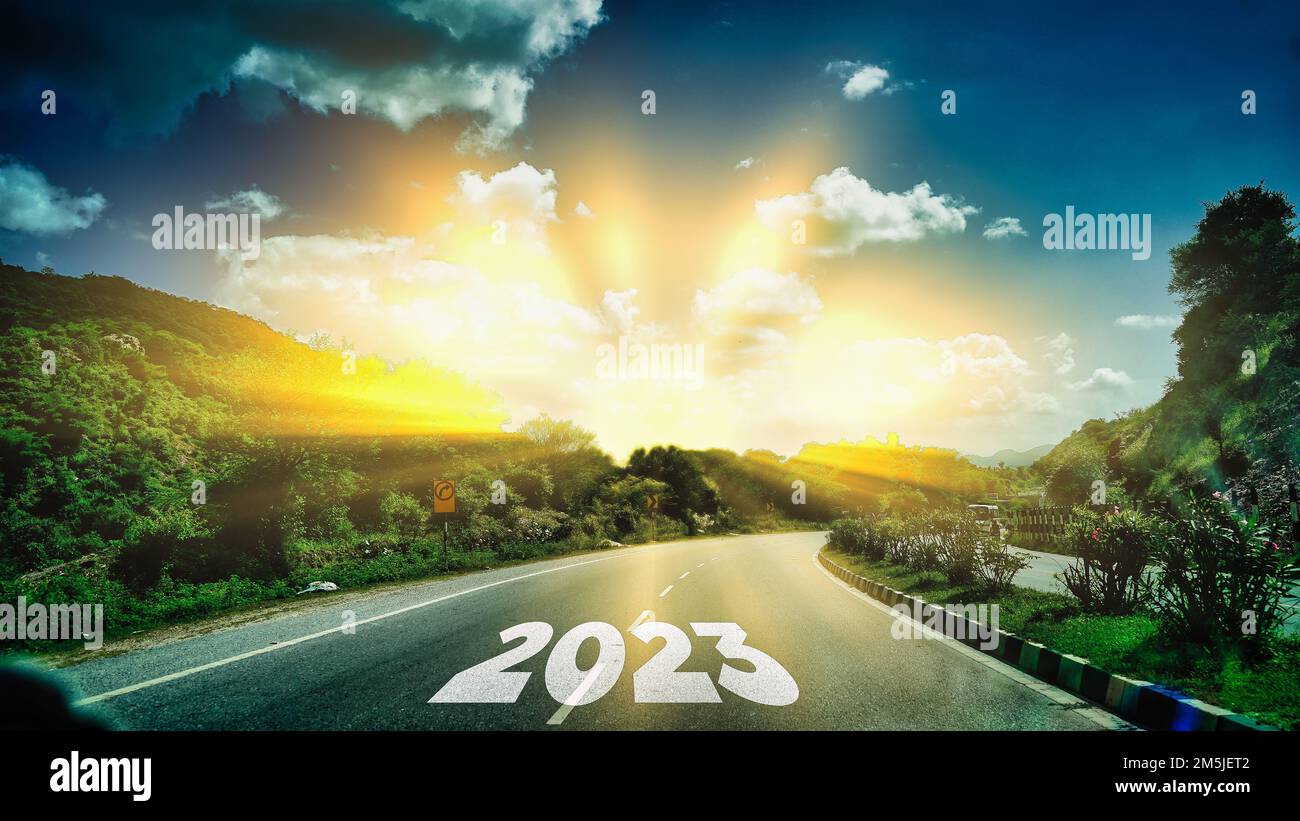 Nouvelle année 2023 ou concept direct. Texte 2023 écrit sur la route au milieu de la route asphaltée au coucher du soleil. Concept de planification, but, défi Banque D'Images