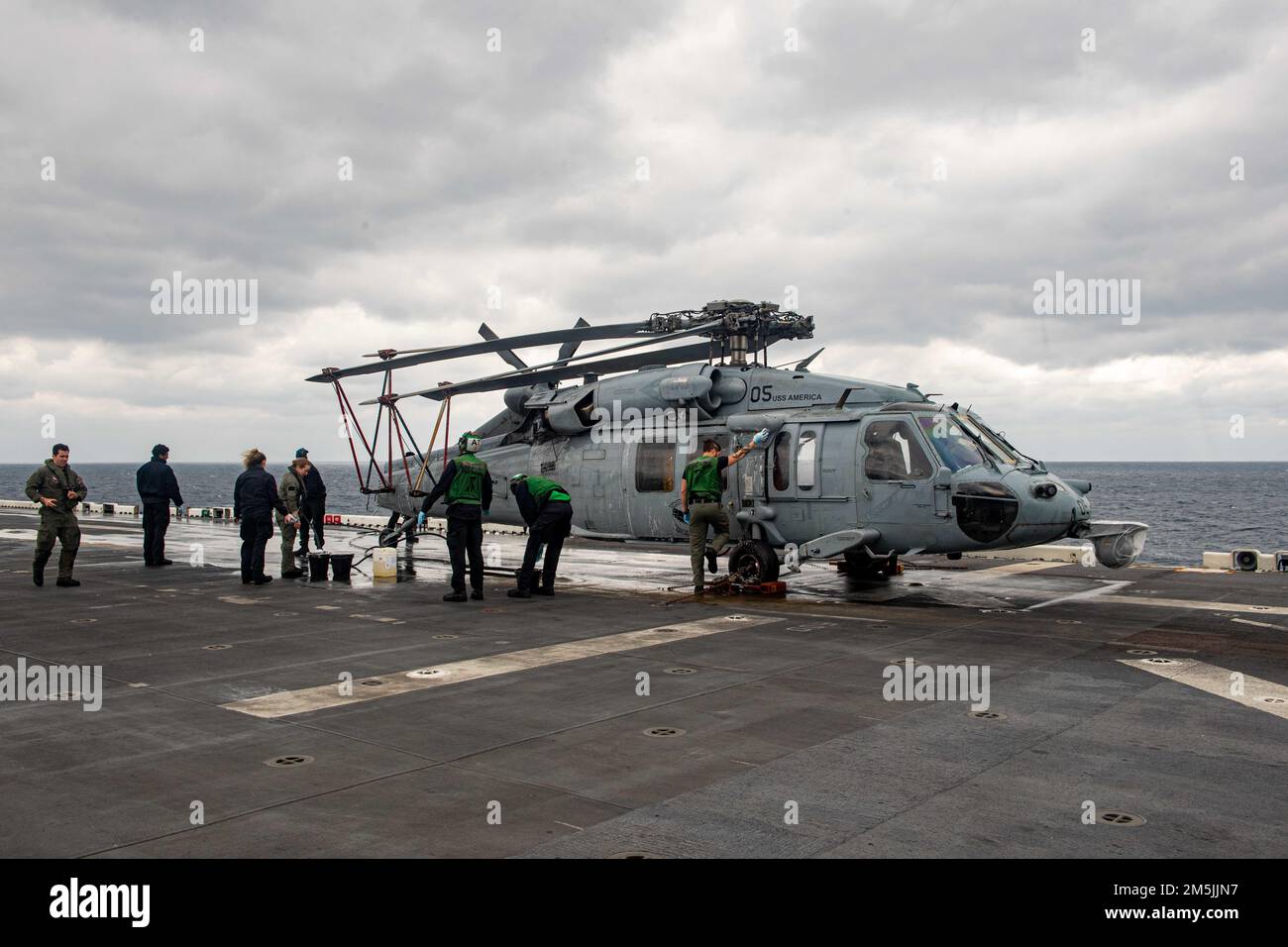 MER DE CHINE ORIENTALE (19 mars 2022) les marins affectés à l'Escadron de combat de la mer d'hélicoptère (HSC) 25 lavent un hélicoptère MH-60s Sea Hawk sur le pont de vol du navire d'assaut amphibie déployé vers l'avant USS America (LHA 6). L'Amérique, navire chef de file du America Amphiobie Ready Group, opère dans la zone de responsabilité de la flotte américaine 7th afin d'améliorer l'interopérabilité avec les alliés et les partenaires et de servir de force de réaction prête à l'emploi pour défendre la paix et la stabilité dans la région Indo-Pacifique. Banque D'Images