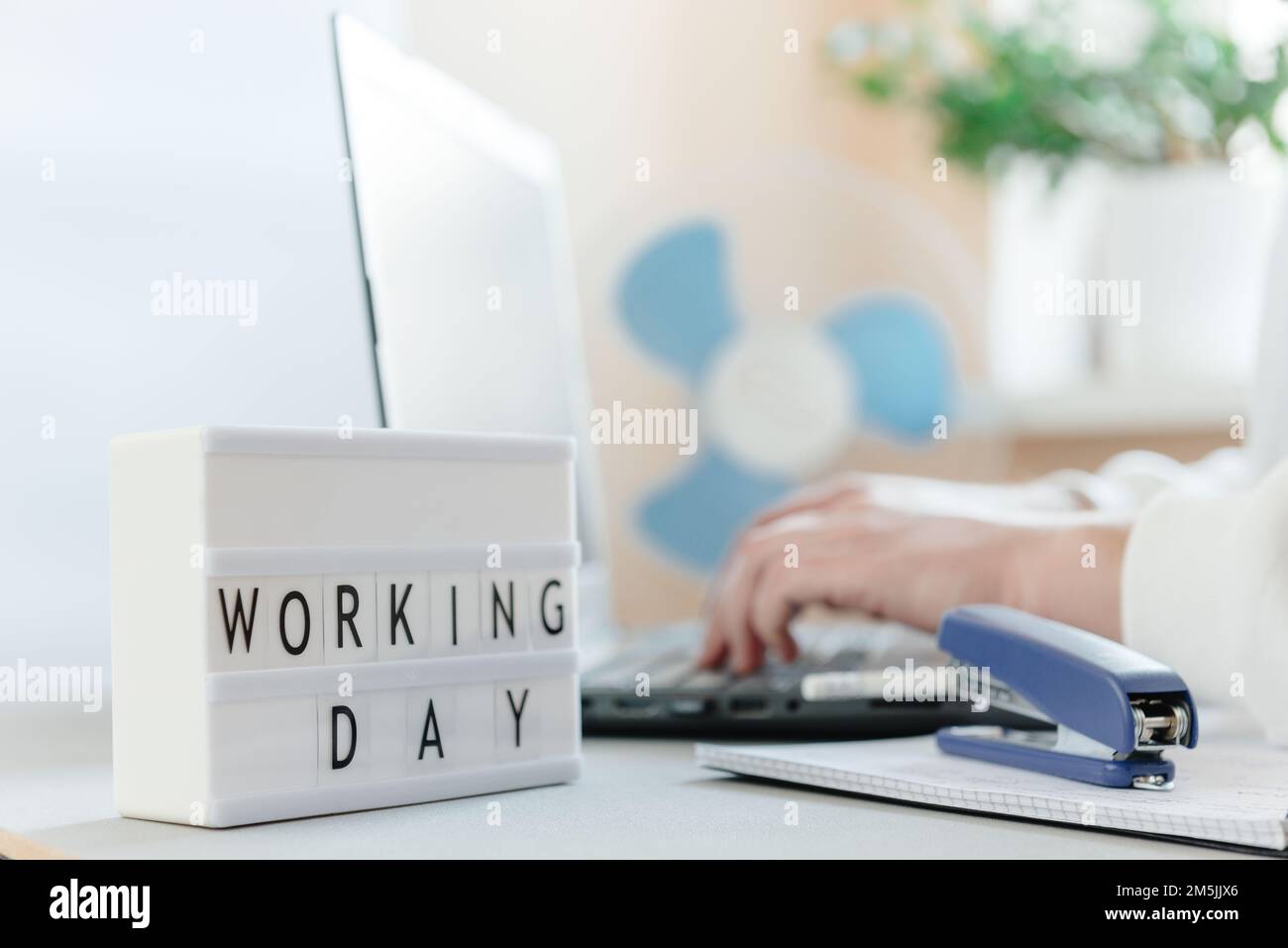 Lieu de travail avec un ordinateur portable, mains d'un homme, bloc-notes sur fond blanc. Le lieu de travail de freelance. Inscription de texte Workday et espace vide pour le texte Banque D'Images