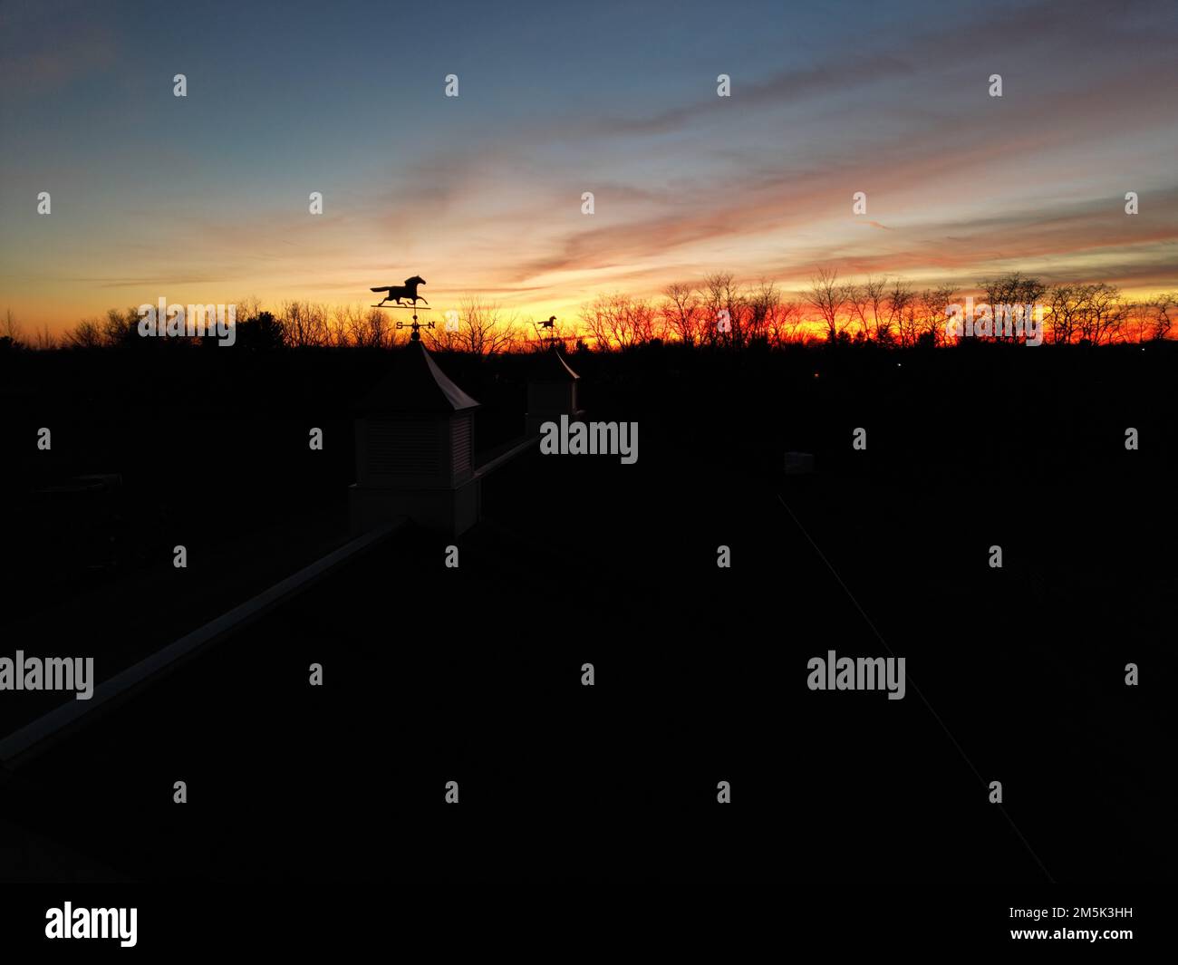 La silhouette de chevaux sur les coupoles et les arbres contre le ciel orange-rouge au coucher du soleil Banque D'Images