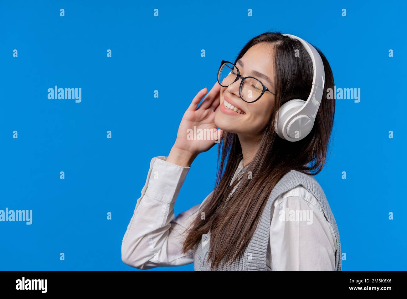 Un adolescent heureux étudiant écoutant de la musique, dansant avec un  casque sur fond de studio bleu. Radio, technologie audio moderne sans fil,  lecteur en ligne Photo Stock - Alamy