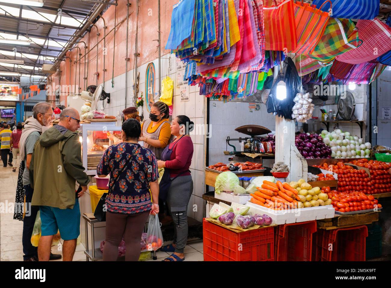 Les gens se dressent dans un stand vendant des viandes préparées au marché Lucas de Galvez, dans le centre de Merida, Yucatan, Mexique Banque D'Images