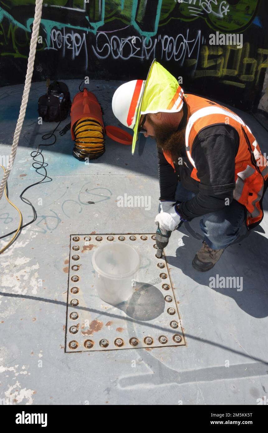 Avant que les travailleurs entrent dans l'espace confiné à l'intérieur du barrage de Sepulveda pour faire leur inspection, Charles Fouty, opérateur de réparation d'équipement de barrage avec les États-Unis Armée corps of Engineers district de Los Angeles, enlève une plaque au-dessus du barrage pour évacuer le gaz causé par la créosote 22 mars à Van Nuys, Californie. Après le retrait de la plaque, de grands flexibles de ventilation ont été insérés pour éliminer toute accumulation de gaz. Le personnel du district a récemment suivi une formation pour travailler dans des espaces confinés. Le barrage a subi une inspection de la structure hydraulique en acier 22-23 mars. (Photo de John Reese, États-Unis Armée corps des ingénieurs Los Angeles Distr Banque D'Images
