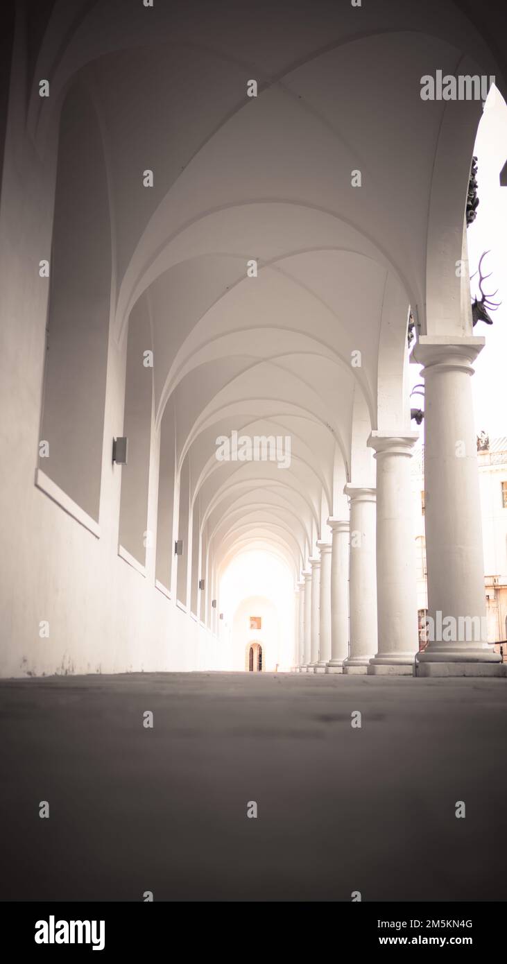 Un couloir avec de grandes colonnes et des arcs blancs au coucher du soleil, vertical, lumière au bout du tunnel Banque D'Images