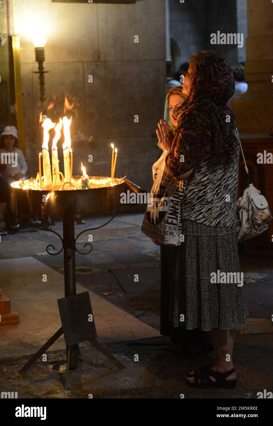 Des femmes éclairent des bougies dans l'église du Saint sépulcre dans la vieille ville de Jérusalem, Israël. Banque D'Images