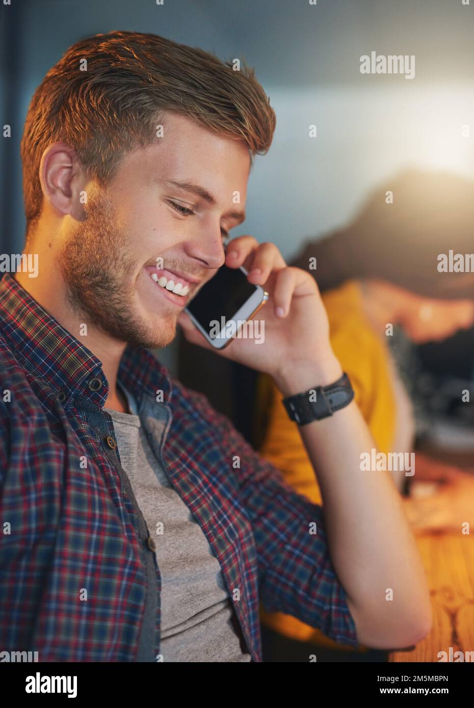 Vous pouvez compter sur moi. un jeune homme utilisant son téléphone portable tout en travaillant tard dans le bureau. Banque D'Images