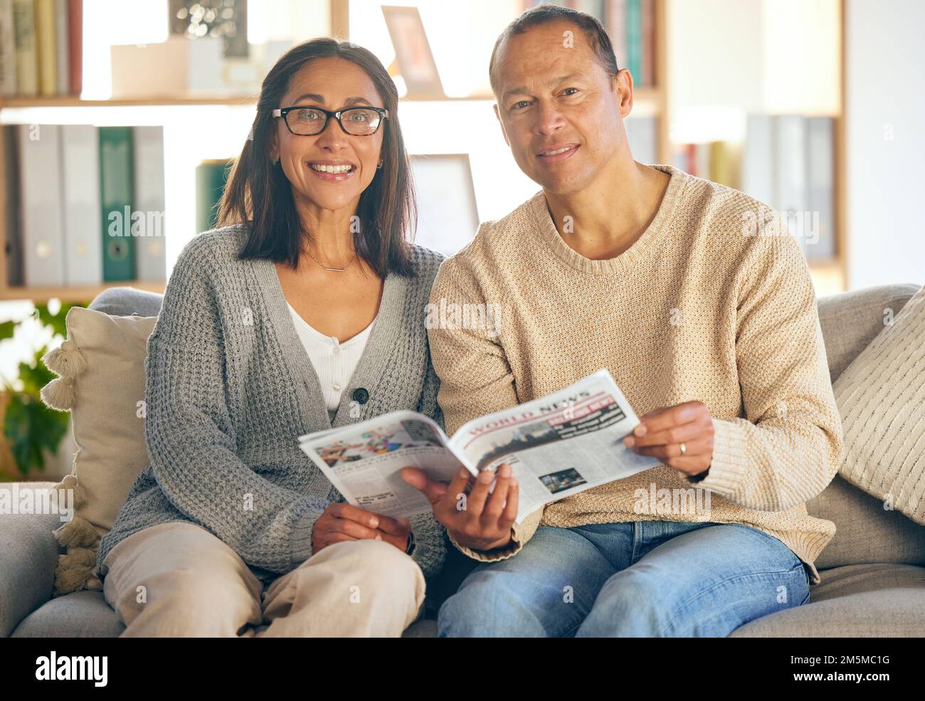 Maison, détente ou couple avec un journal ou un magazine lisant des informations politiques locales tout en se reposant sur un canapé de salon. Portrait, portrait ou heureux Banque D'Images