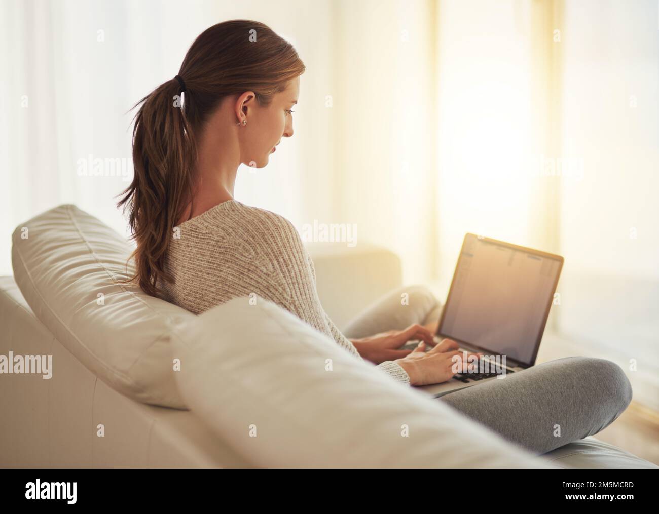 Rattraper tous ses blogs. une jeune femme utilisant son ordinateur portable à la maison. Banque D'Images