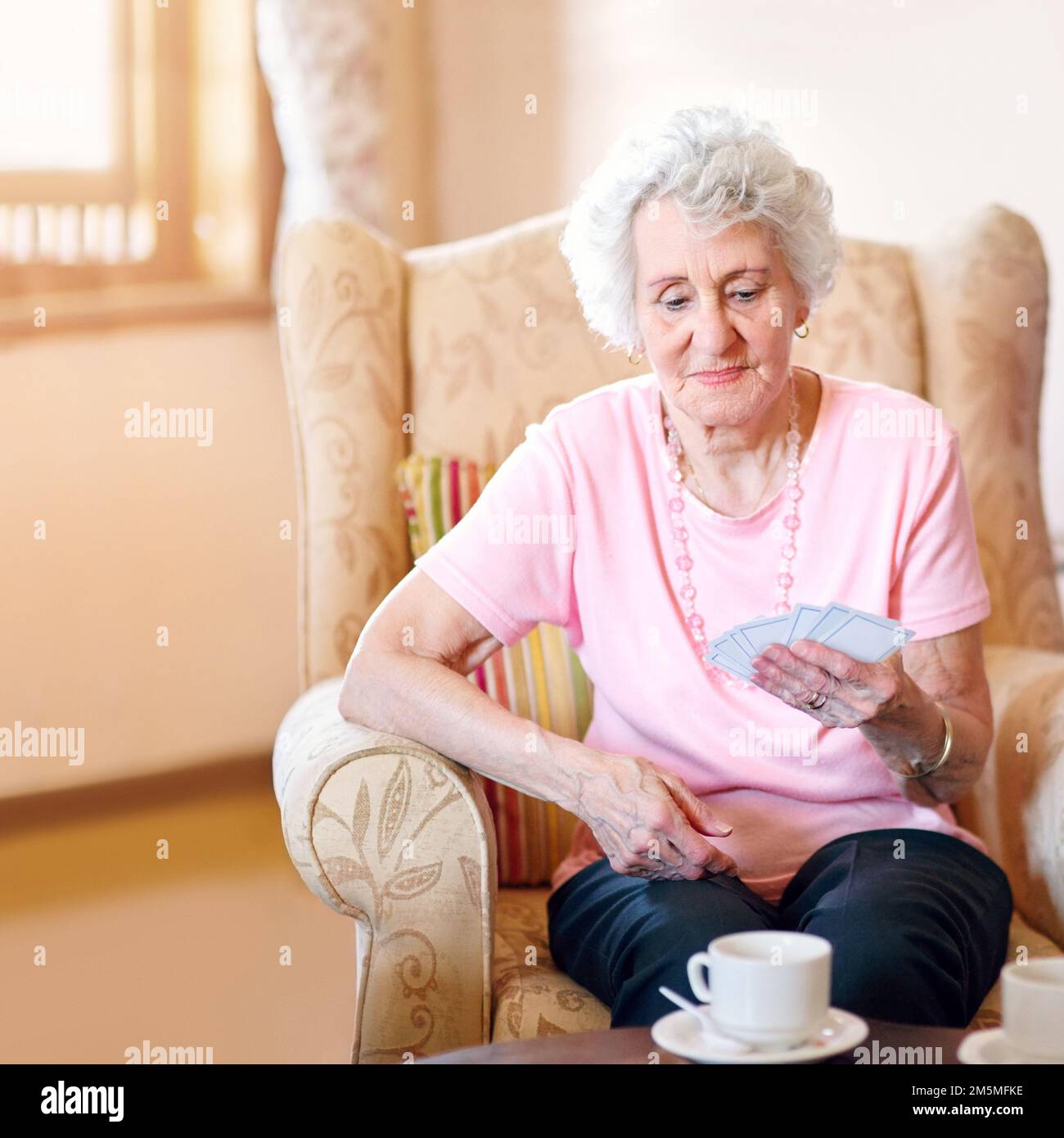 J'ai l'air d'une main gagnante. une femme âgée heureuse regardant ses cartes pendant un match avec ses amis dans une maison de retraite. Banque D'Images