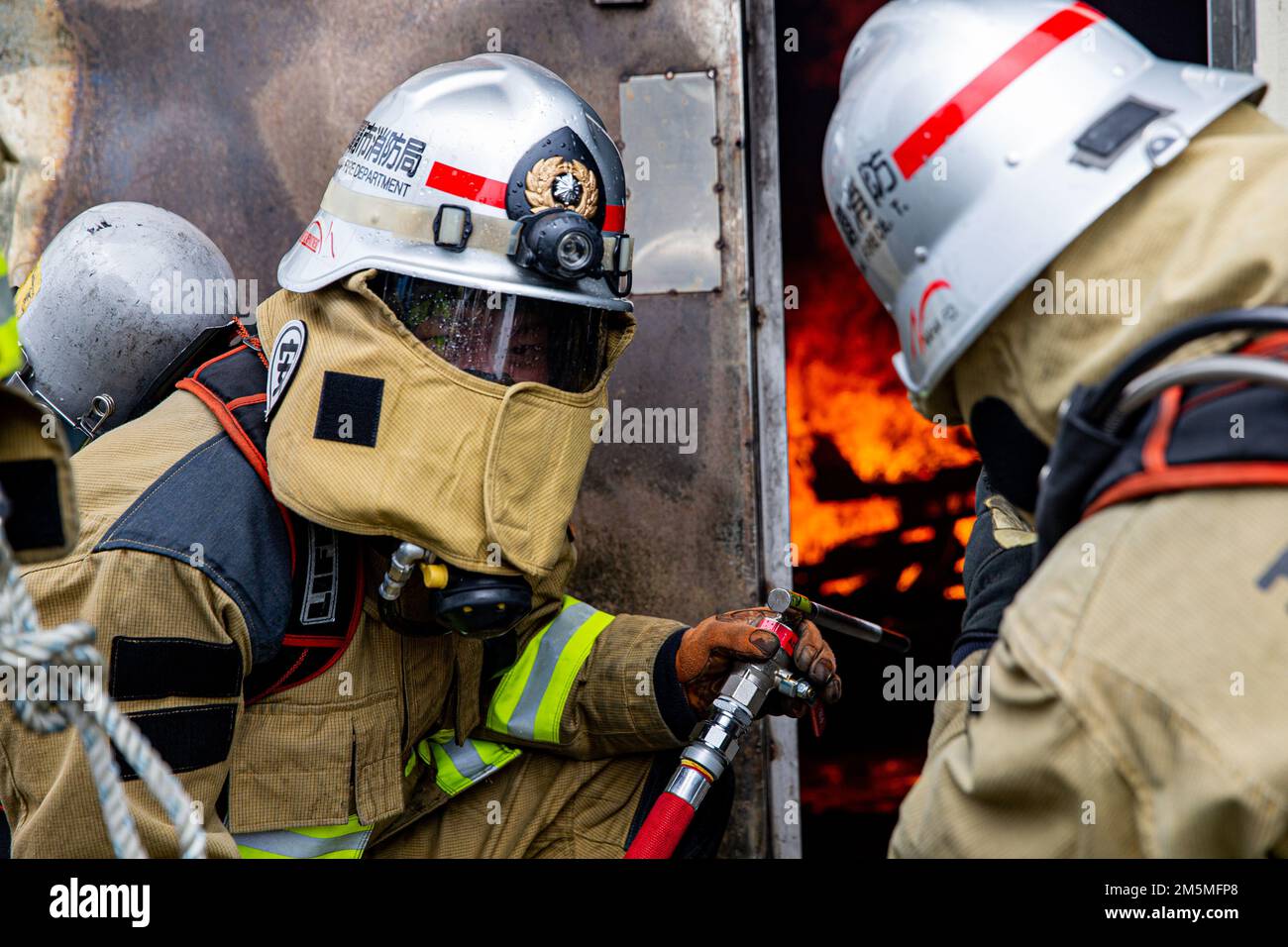 Les pompiers du service des incendies de la ville de Naha réagissent à un incendie lors d'un exercice bilatéral d'entraînement en direct sur le camp Hansen, Okinawa, Japon, 25 mars 2022. Les installations des corps maritimes les Services d'incendie et d'urgence du Pacifique et le Service des incendies de la ville de Naha ont rassemblé et organisé une formation en direct sur les incendies afin de comparer les différentes techniques et méthodes de lutte contre les incendies utilisées par chaque ministère pour accomplir la même mission. Banque D'Images